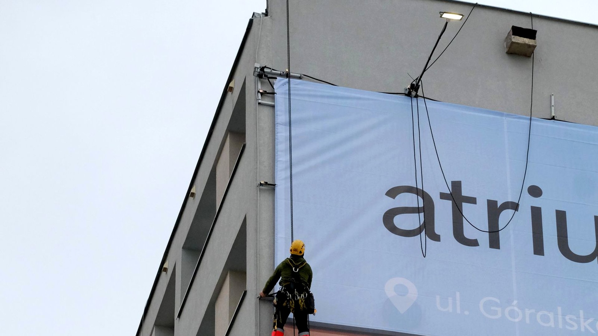 Sign installer securing a large commercial building graphic
